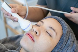 A woman undergoing ultrasound treatment on her face.